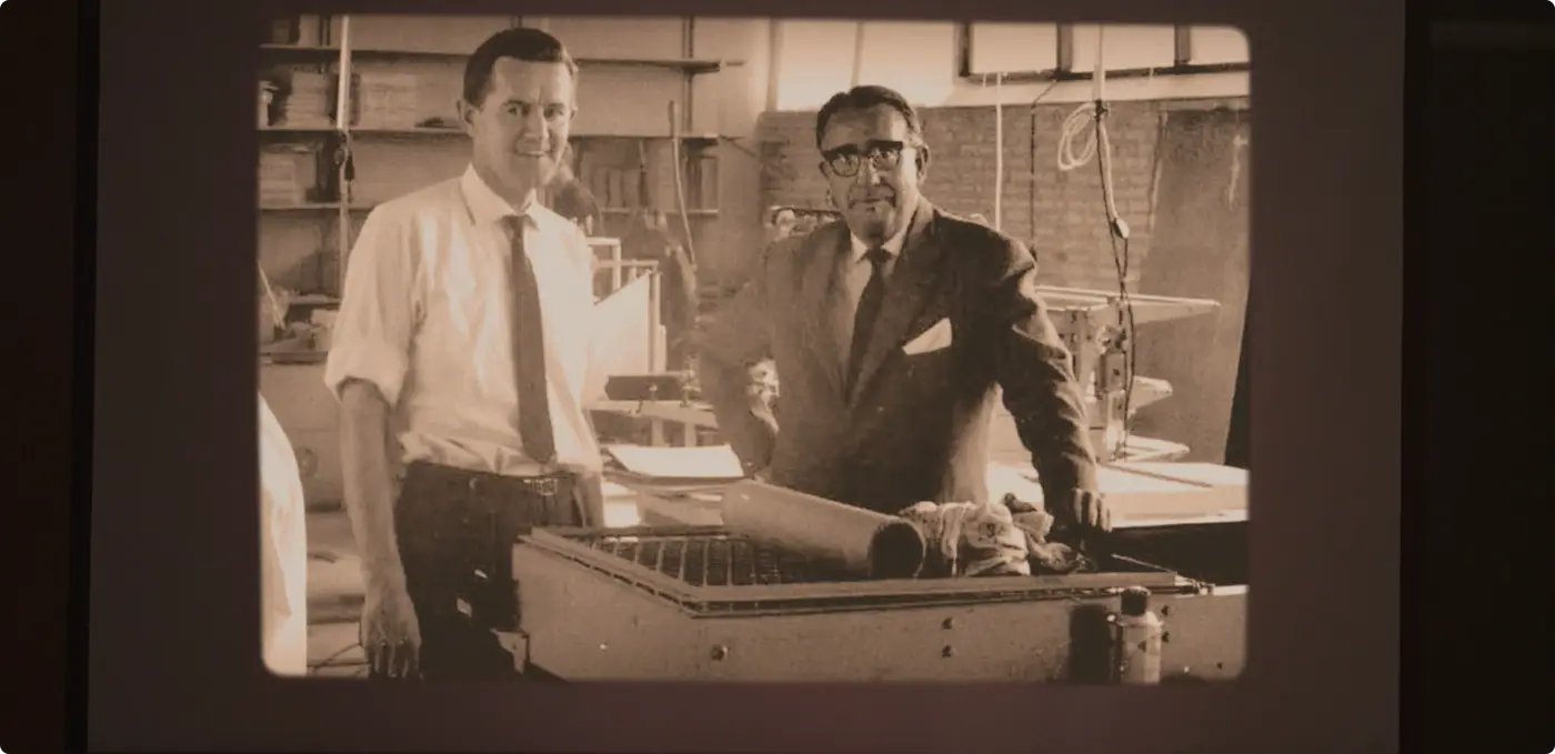Aage Louis-Hansen standing with a colleague in front of machinery, in a factory setting in the 1960s.